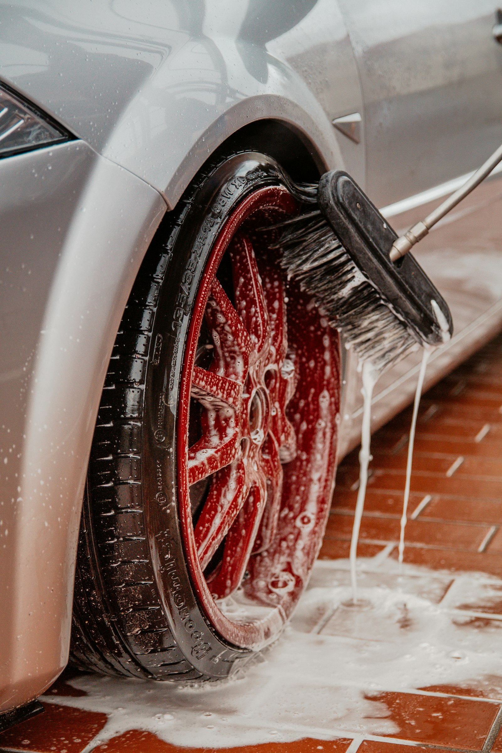 Close-up of a wheel being scrubbed with a soap-covered brush
