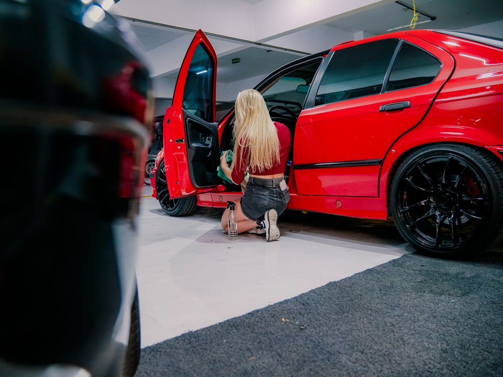 A detailer wiping down the wheel of a red car
