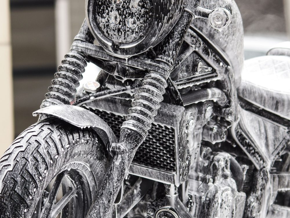 A motorcycle covered in cleaning foam during a wash