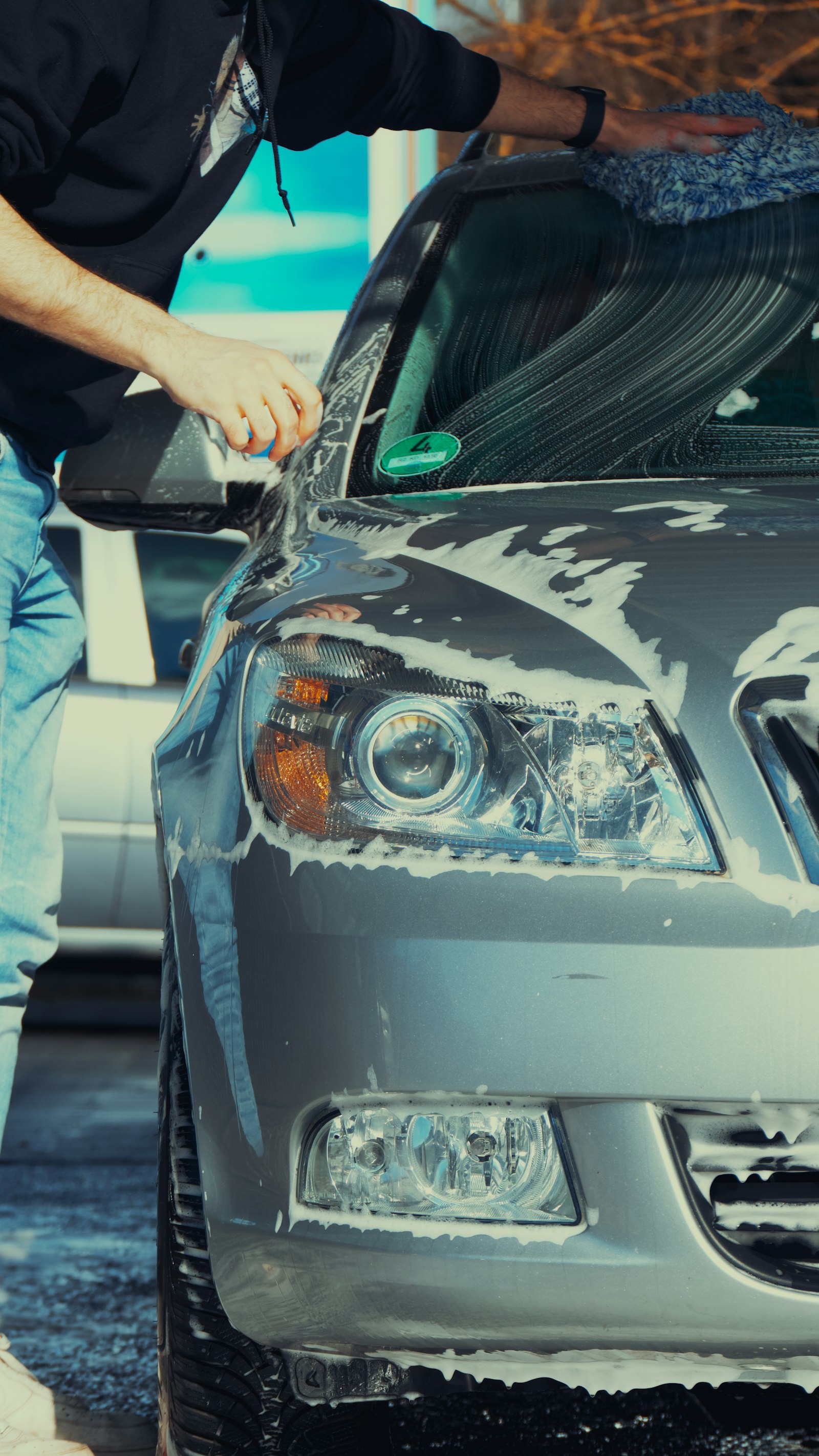 Wiping down a soapy sedan headlight with a microfiber towel