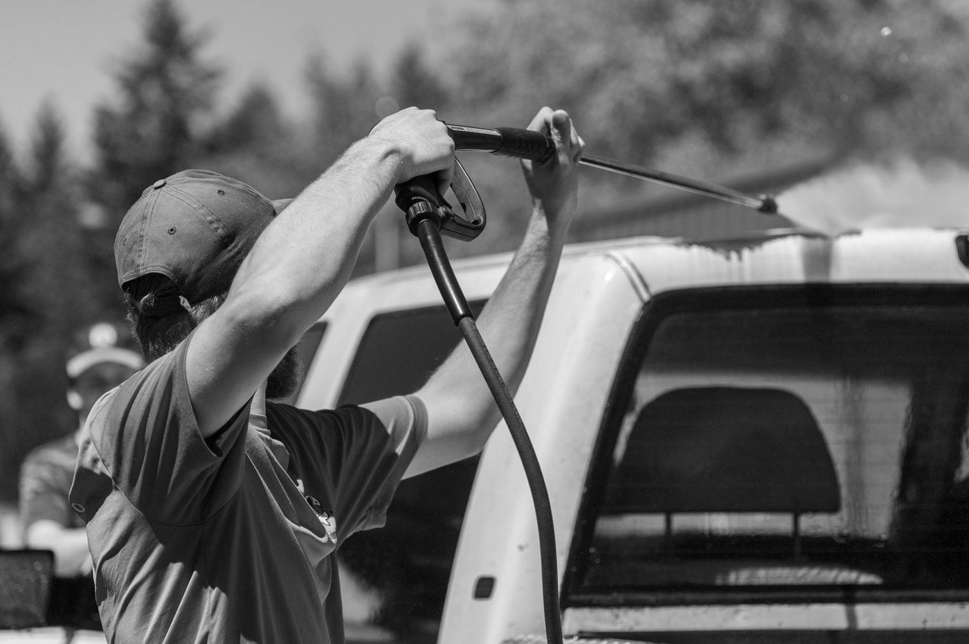 A detailer pressure-washing a pickup truck
