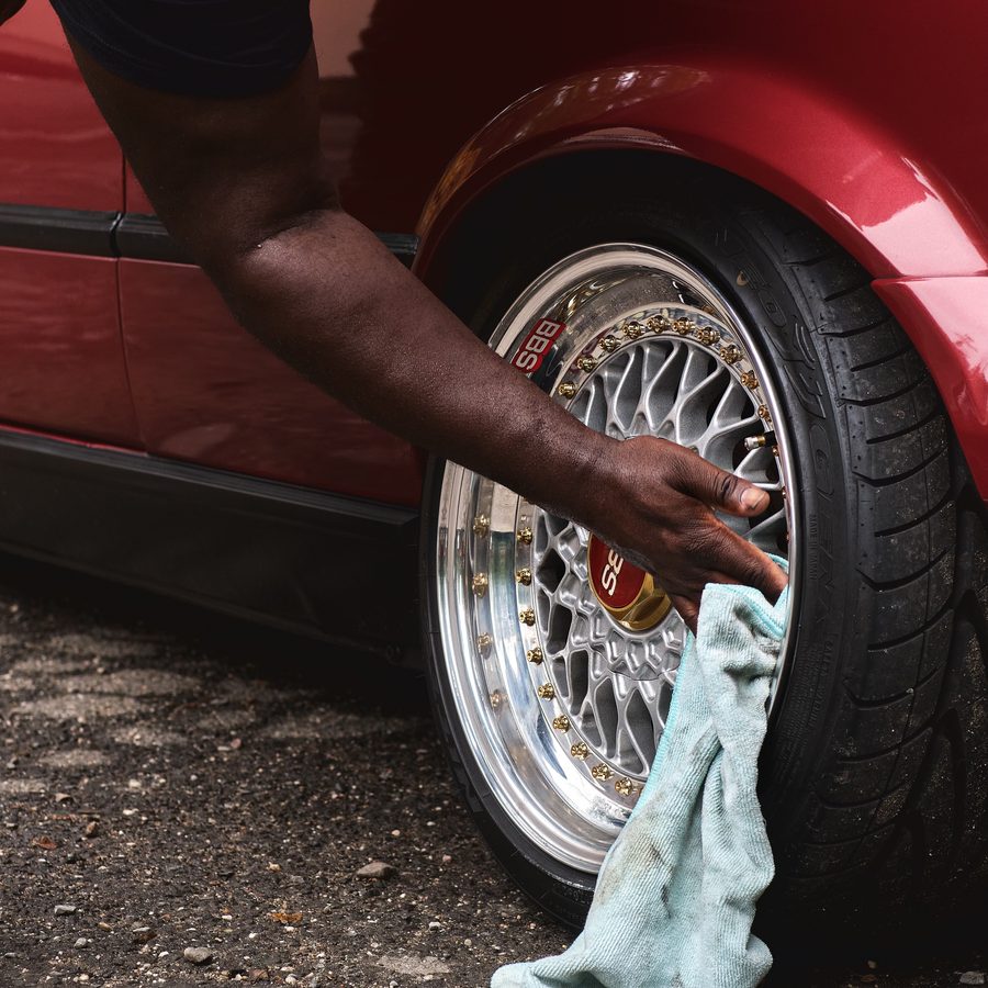 A hand wiping down a polished alloy wheel
